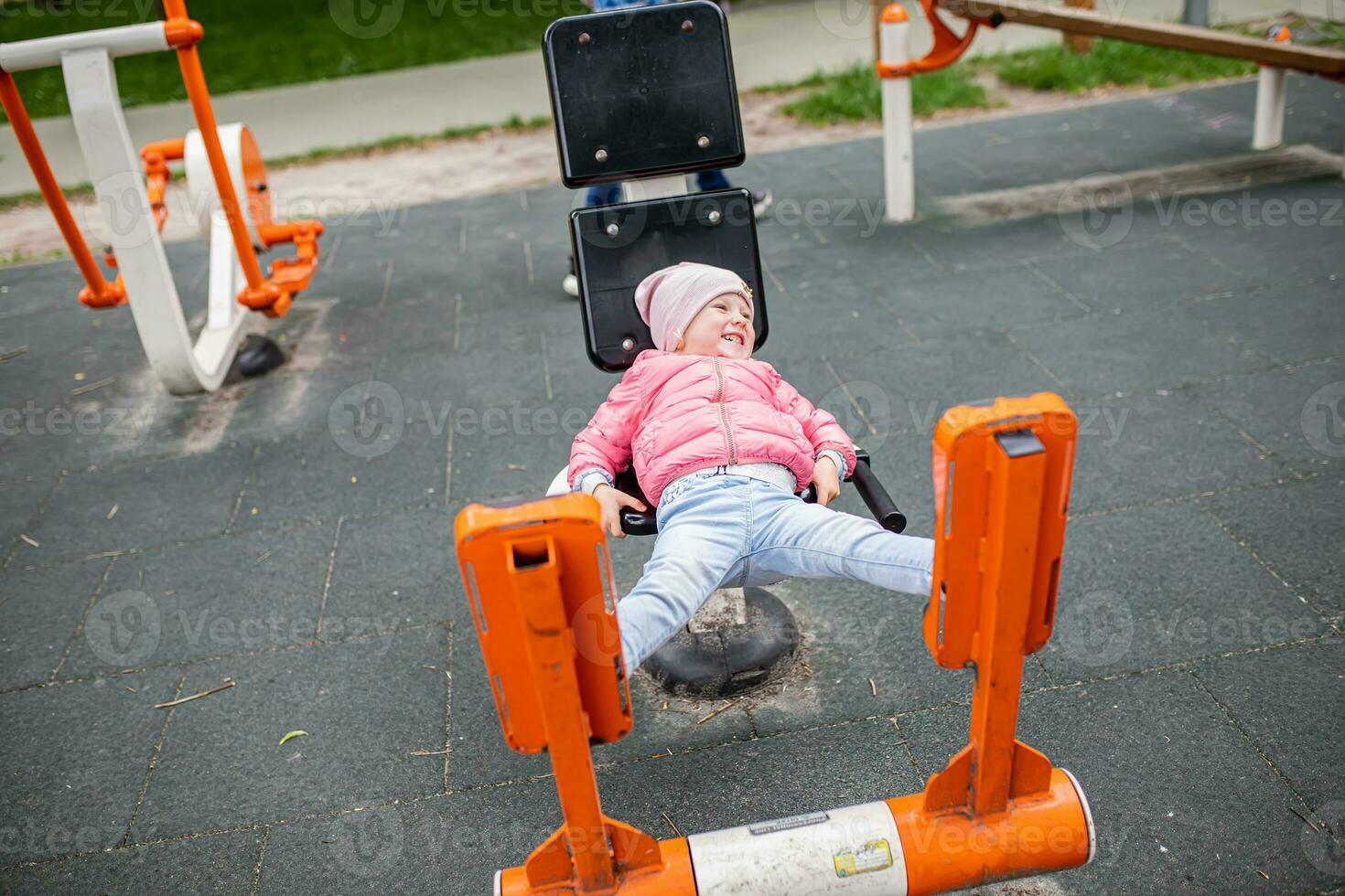 Girl doing exercises on the outdoor exercise machines LEG PRESS, lying on an armchair and resting their legs. Easy-to-use cardiovascular fitness equipment at sports ground in the city park photo