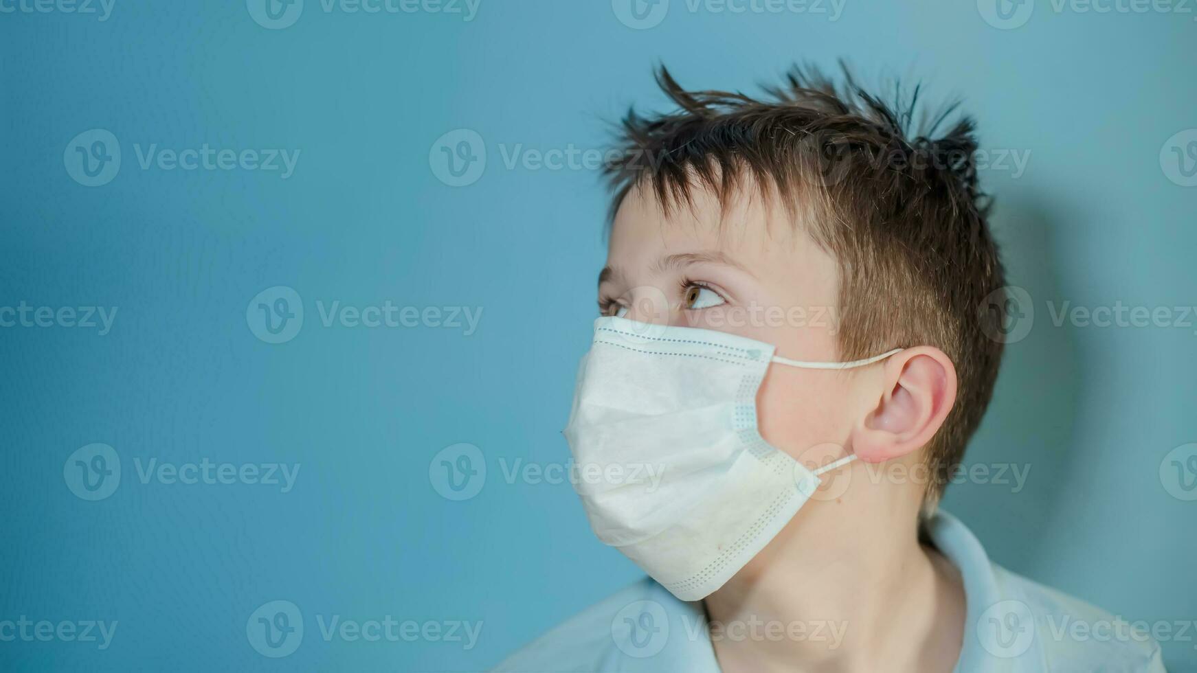 boy in medical mask turned sideways and looked up. child with flu, influenza or cold protected from viruses, among patients with coronavirus. photo