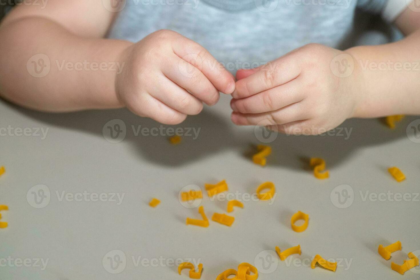 hand of child collecting letters from pasta from table. development of fine motor skills of hands. Montessori technique. Learn letters and alphabet in game photo