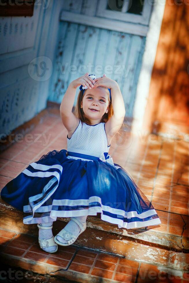 Beautiful girl was heart-shaped handles. The child sits on the stairs of the old house. Girl on a background window old house in the village. Baby illuminated rays of the setting sun. photo