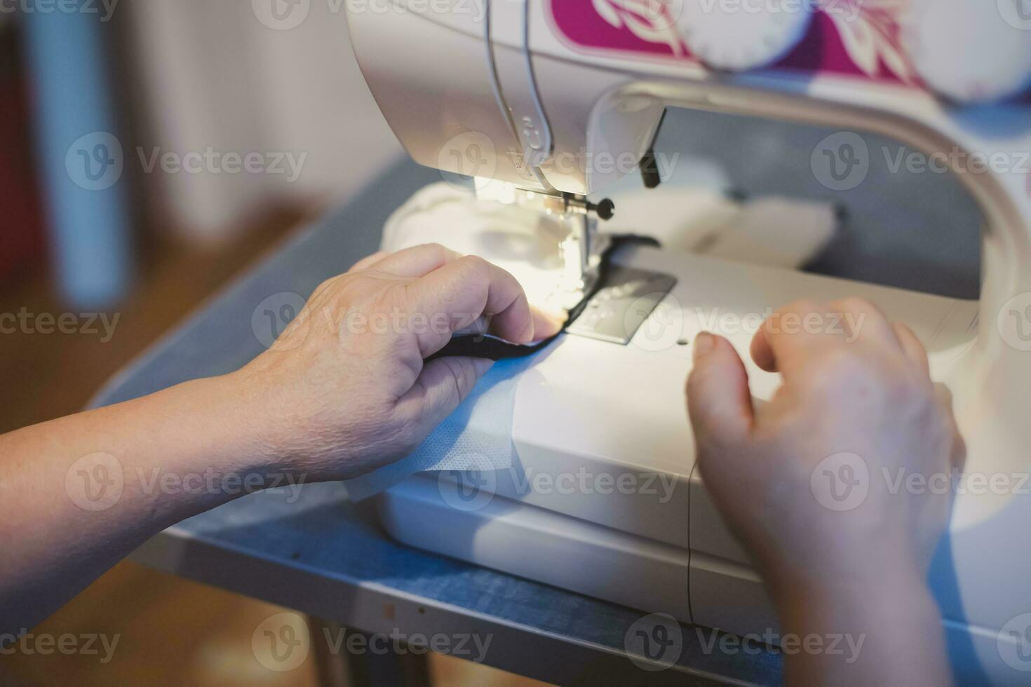 woman's hand that sifts protective homemade face mask on sewing machine. DIY fabric cotton Coronavirus face masks. Stack Mask Cloth Face Coverings to Help Slow Spread of COVID-19 photo