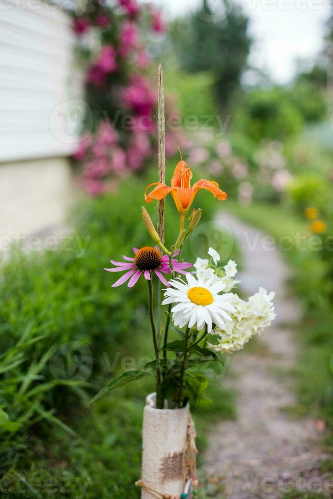 ramo de flores de verano flores en un florero en pie en un sendero cerca el casa foto