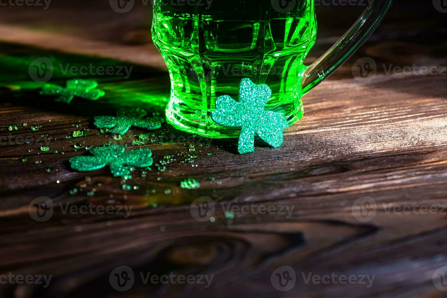 clover leaves with splashes of cold beer on a wooden table. A glass of green traditional beer on St. Patrick's Day in an Irish pub photo