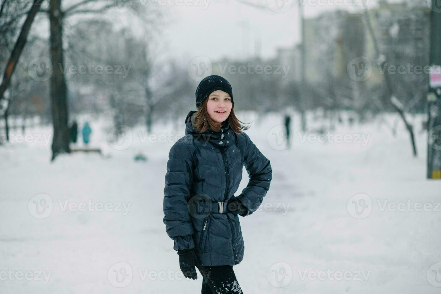 un niña con un mano en su cinturón. un niño en un cubierto de nieve la carretera en el ciudad. ciudad después nevada. foto