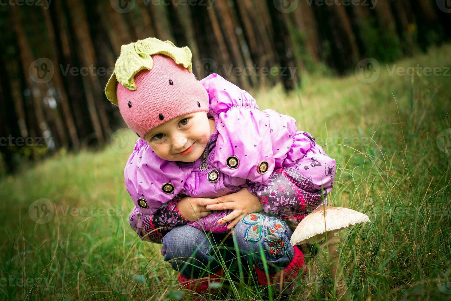 The girl sitting next to a mushroom toadstool. Girl on a background of forest. Big mushroom in the grass. photo