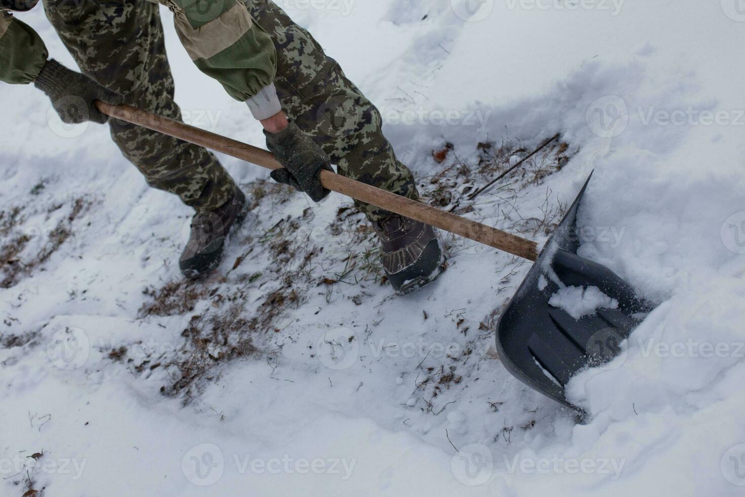 man clears the yard of snow With Shovel. Heavy snowfall in winter. High level of snow. Snowy snowdrift. photo