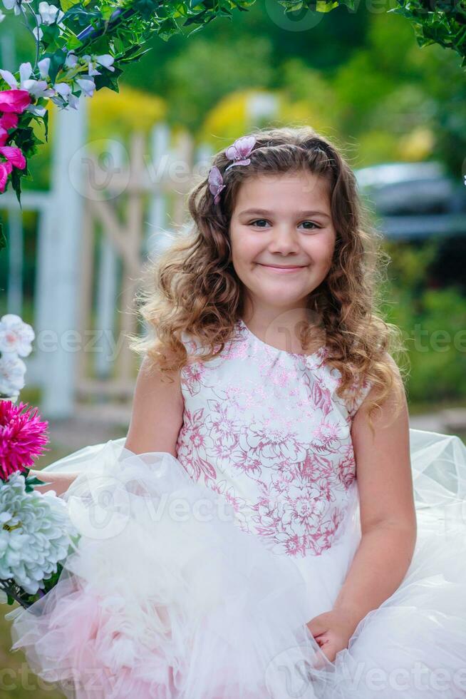 emocional pequeño niña en vestir posando con flores foto