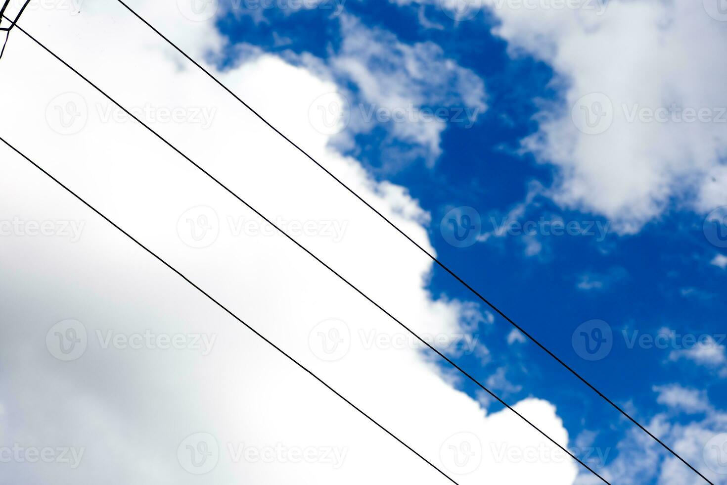Electric wires against sky. White fluffy clouds in blue sky in summer. Background with cloud. photo