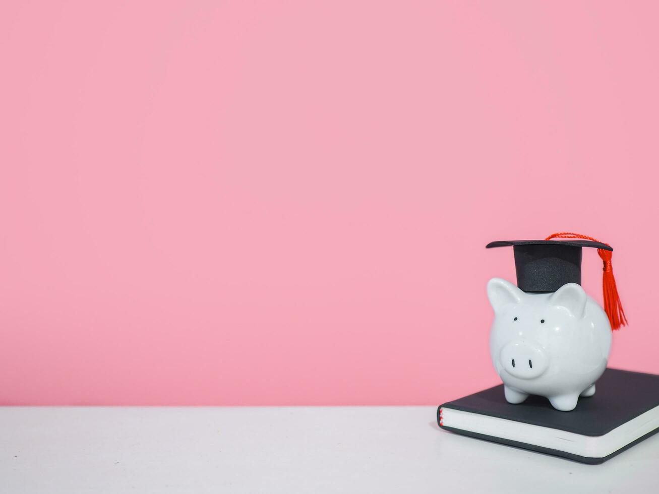 Piggy bank with graduation hat on black hardcover book, Copy space for text, Back to school, Education concept photo