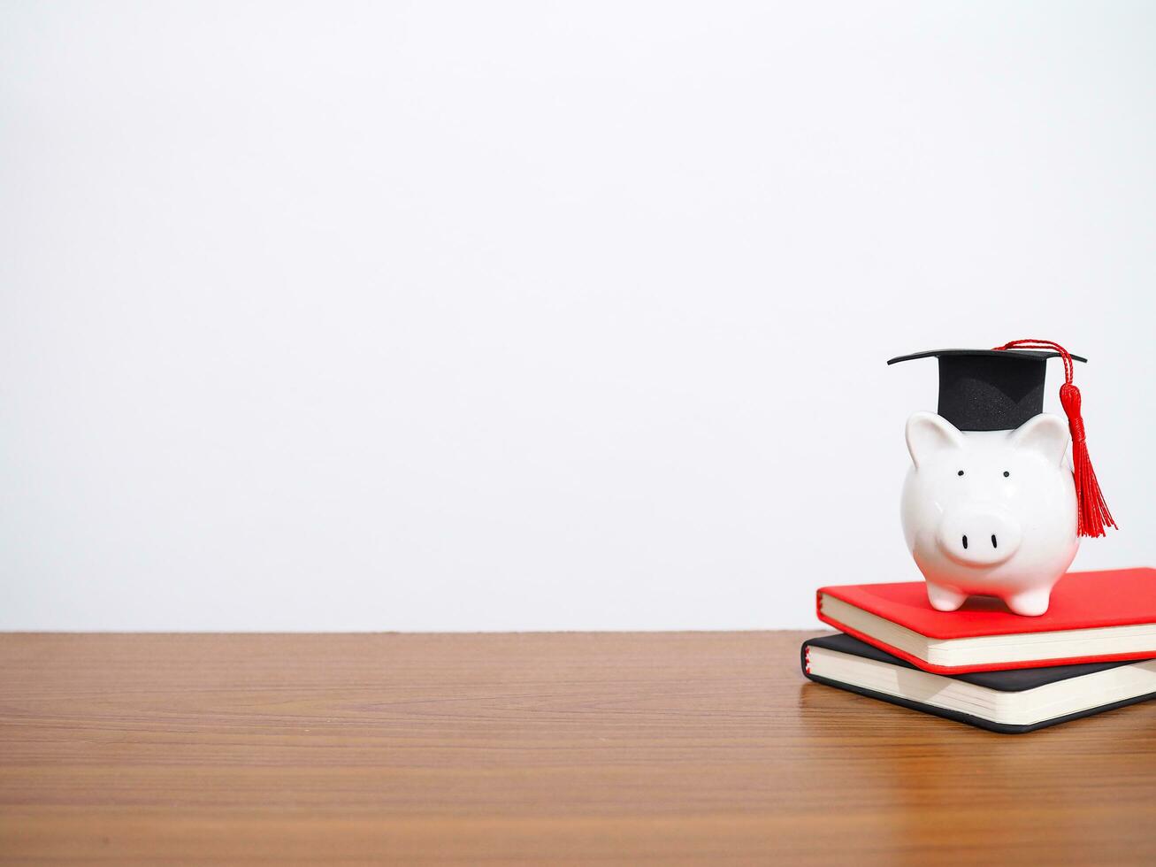 Piggy bank with graduation hat on hardcover book, Copy space for text, Back to school, Education concept photo
