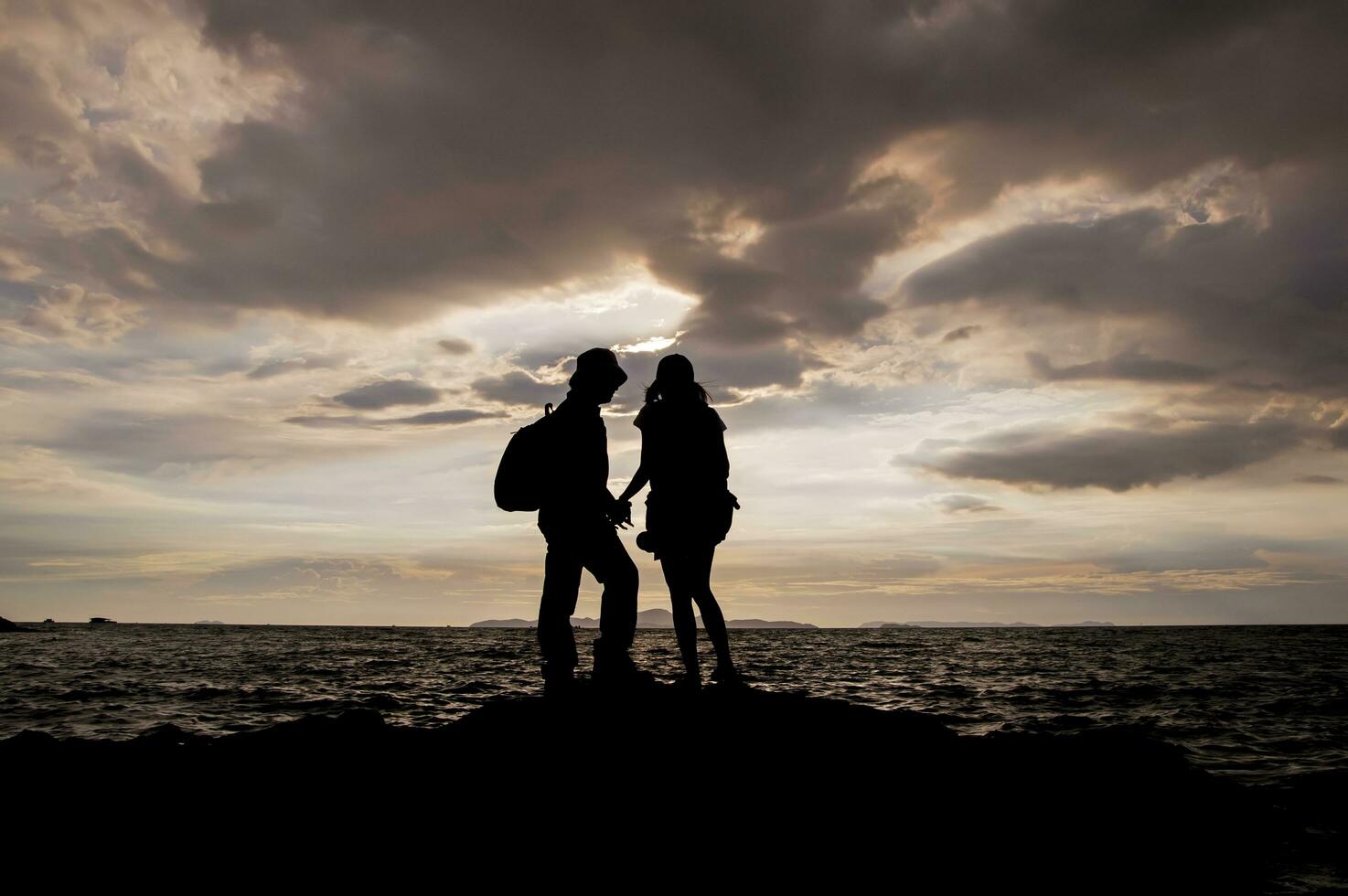 silueta de Pareja en pie en el playa a puesta de sol foto