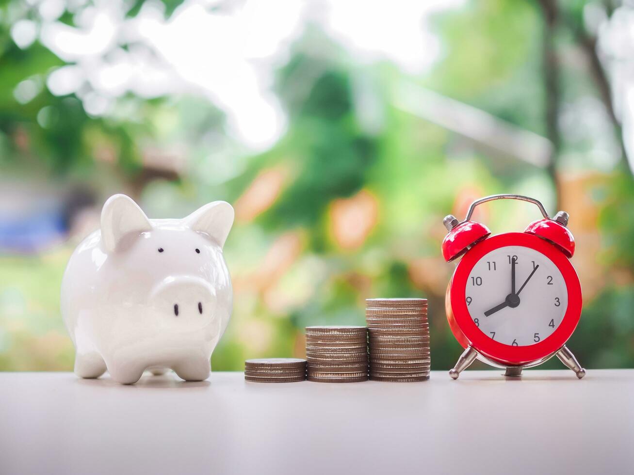Time is money concept. Red alarm, Piggy bank and stack of coins. Save money for prepare in the future. photo