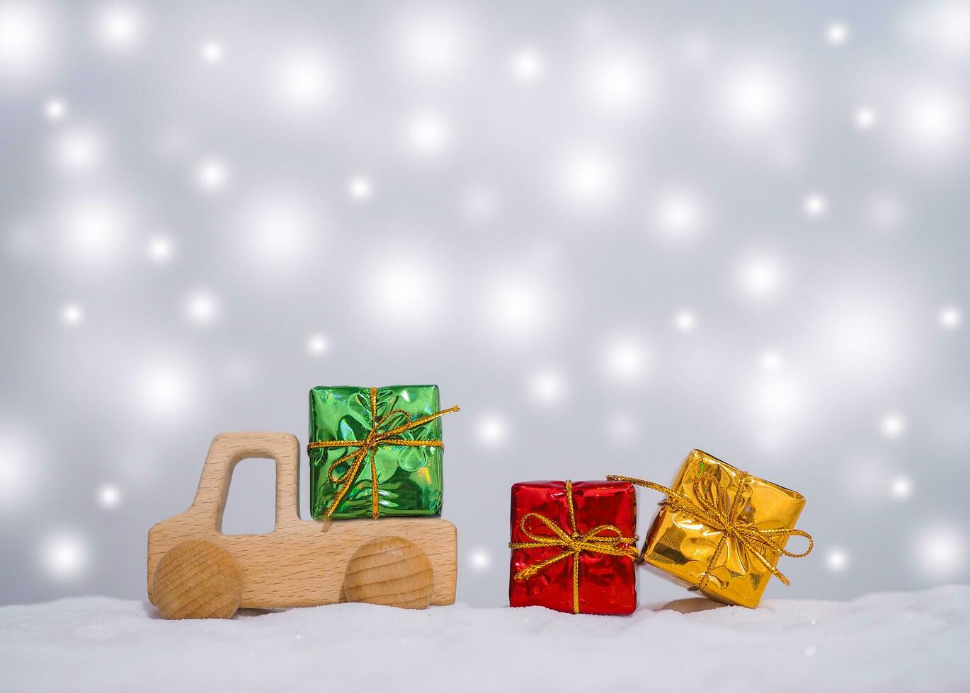 Wooden toy car and gift box with shiny light for Christmas and New Year holidays background, Winter season, falling snow, Copy space for Christmas and New Year holidays greeting card. photo
