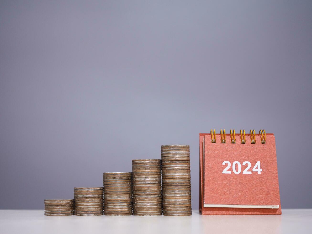2024 desk calendar with stack of coins. The concept of saving money, Financial, Investment and Business growing in new year 2024. photo
