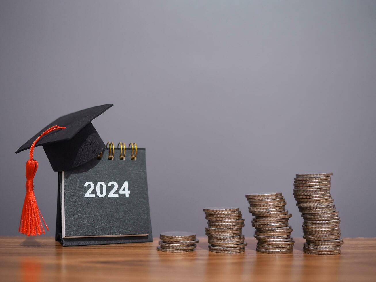 Study goals, 2024 Desk calendar with graduation hat and stack of coins. The concept of saving money for education, student loan, scholarship, tuition fees in New Year 2024 photo