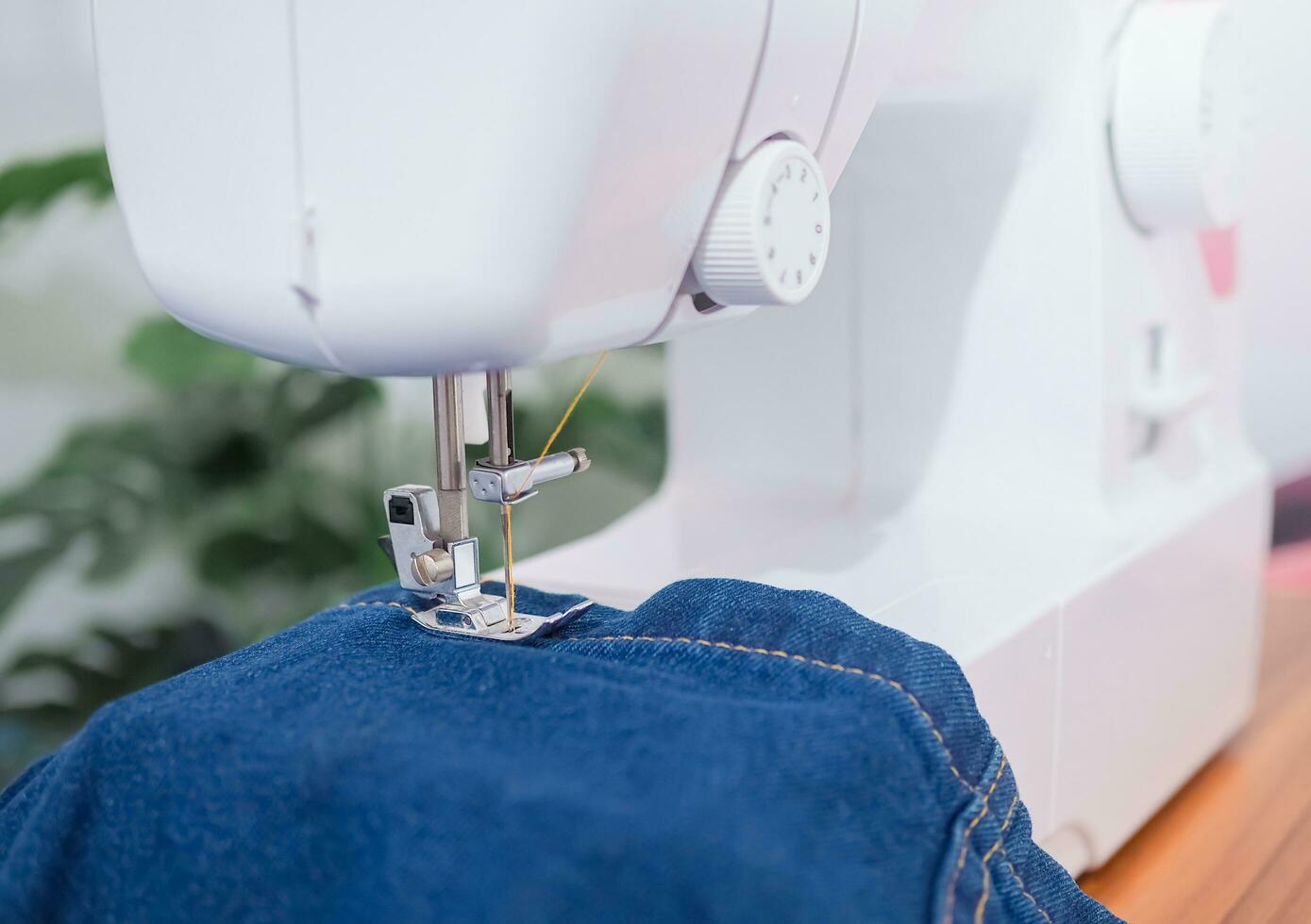 Close up sewing machine sew seam of blue denim jean. photo