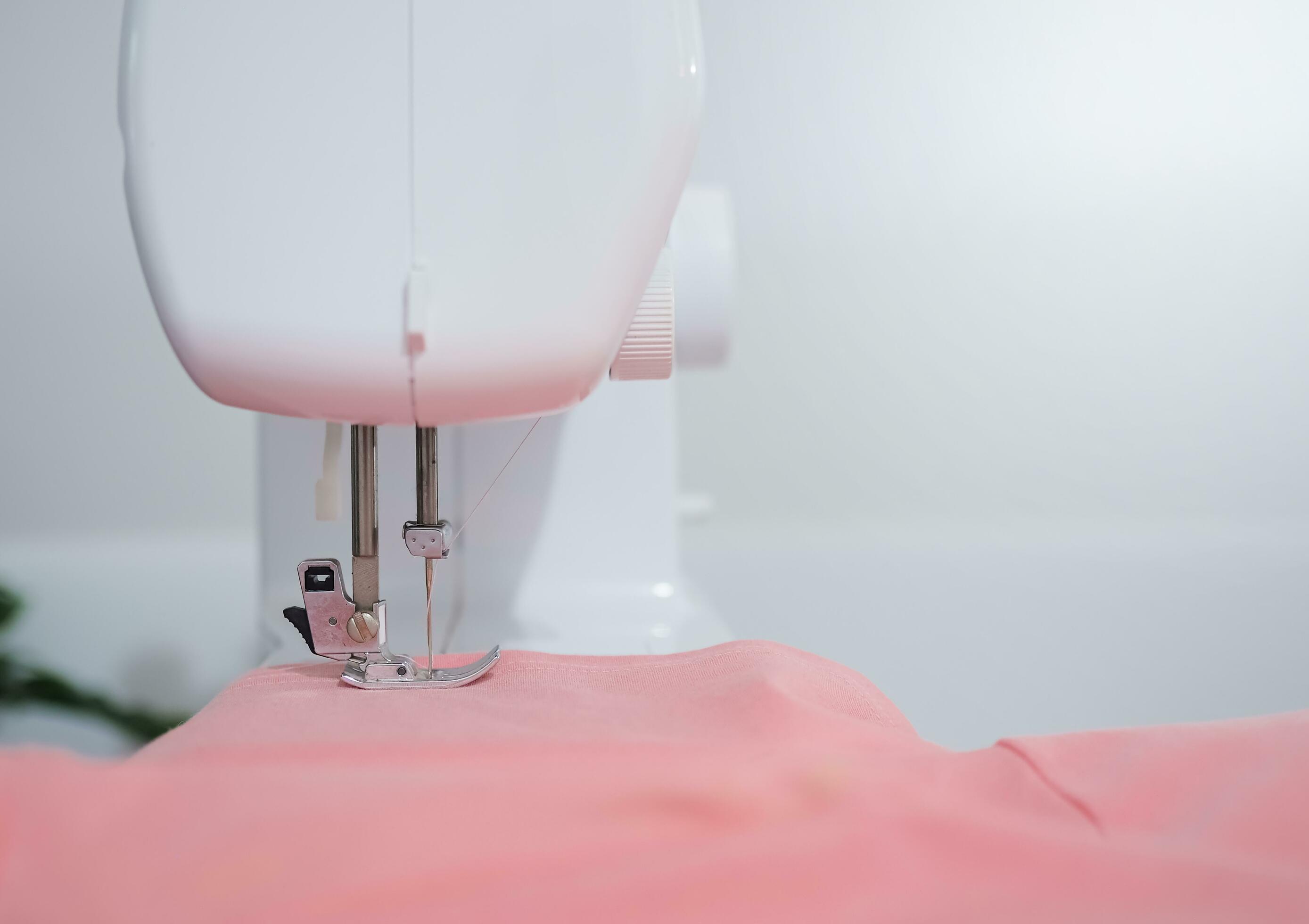 Close up of sewing machine working with pink fabric, stitch new