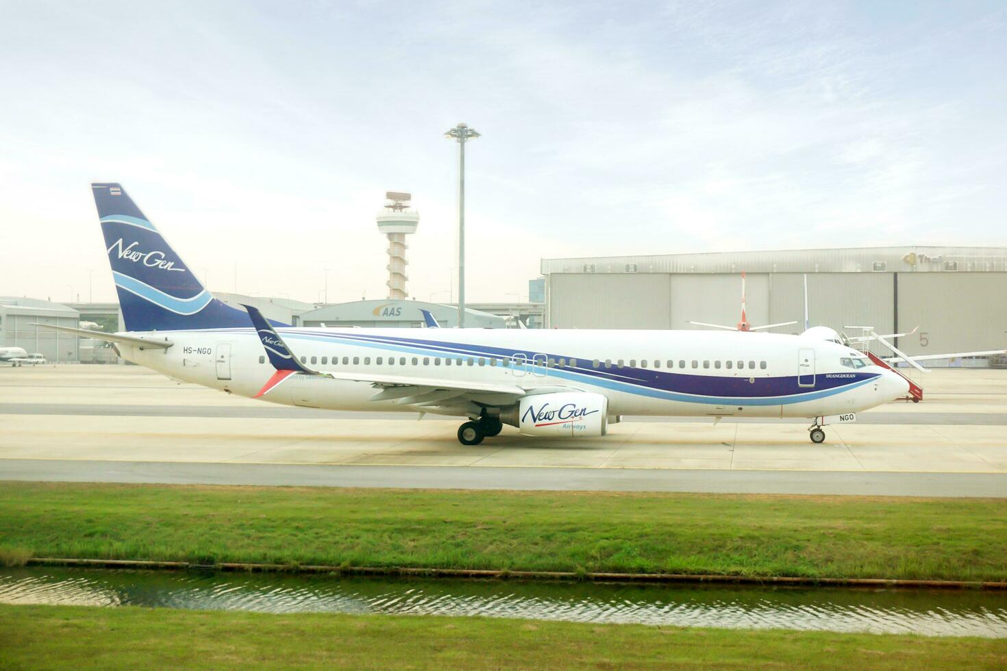 Bangkok City, BKK, 2020 - Side view of New gen aircraft landing and slow running to terminal parking on airport runway under bright blue sky with cloud. photo