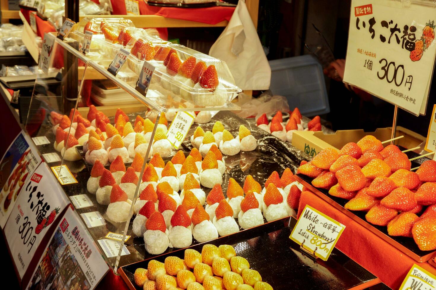 Osaka City, OSK, 2018 - Big mochi filled with strawberries in a display cabinet with Japanese price and name labels. Colors and shapes inviting tourists to buy at the Kuromon Ichiba Market. photo