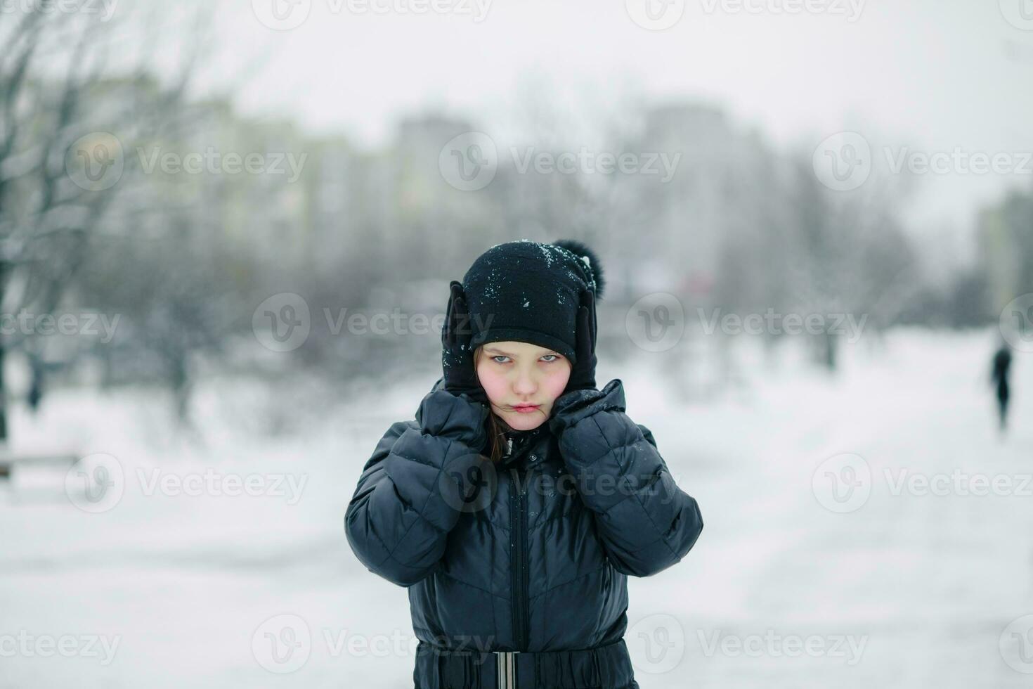 girl covered her mouth with gloves. girl made a gesture, silence. child walks after school on street in a snowfall. photo