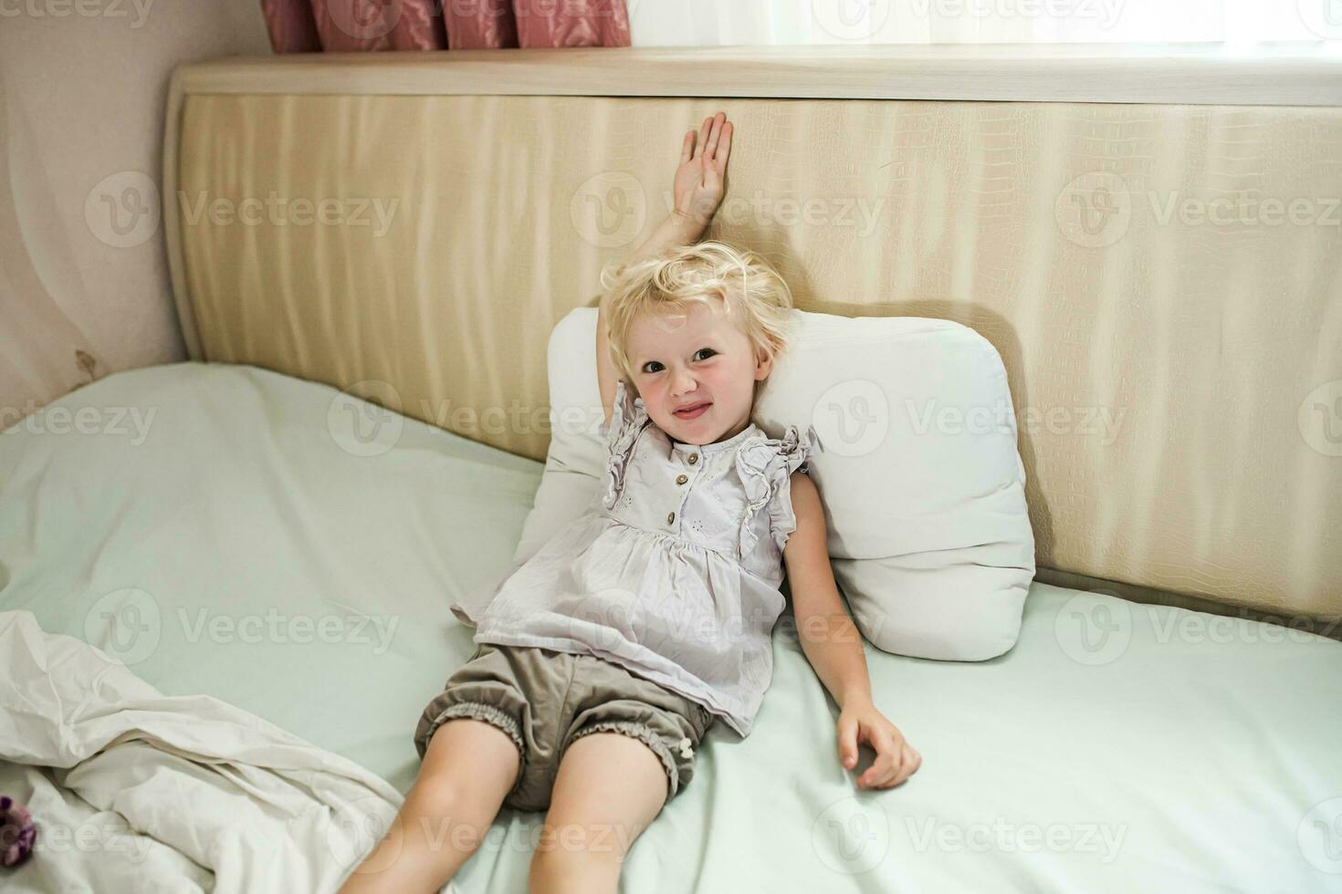 satisfied girl lies on bed with head up. Children's emotions and experiences photo
