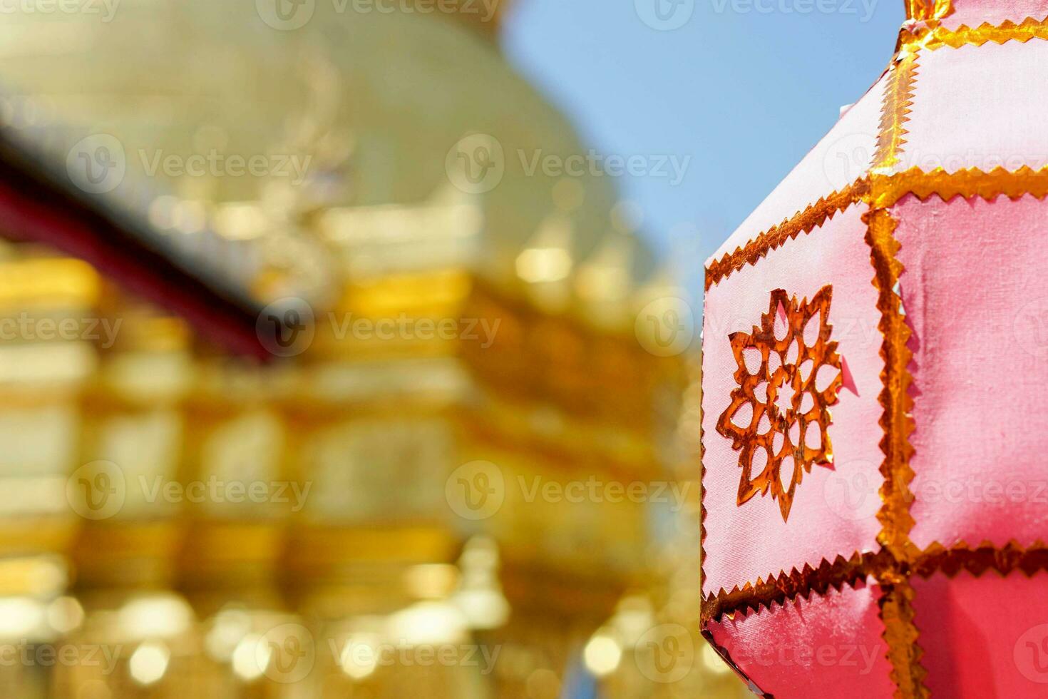 Closeup Thai Lanna style lanterns to hang in front of the golden pagoda at Thai temple under blue sky background. photo