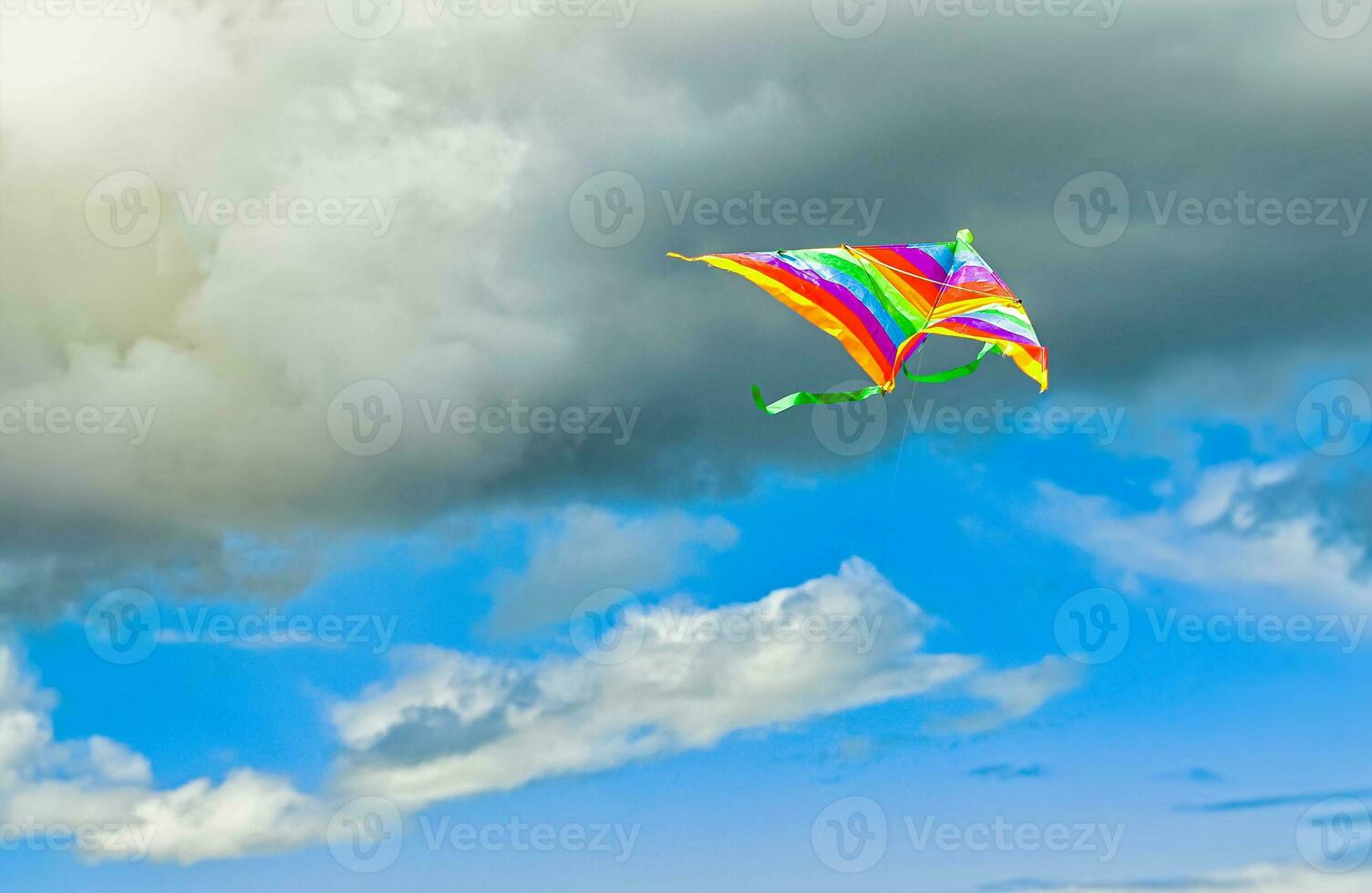 rainbow kite flying in blue sky with clouds in summer with copyspace photo