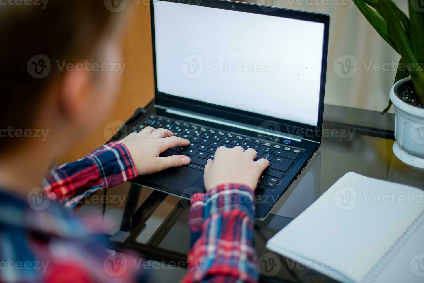 child hands on keyboard of laptop with light empty screen. boy is trained at home remotely during coronovirus quarantine. child is engaged online. Copy space photo