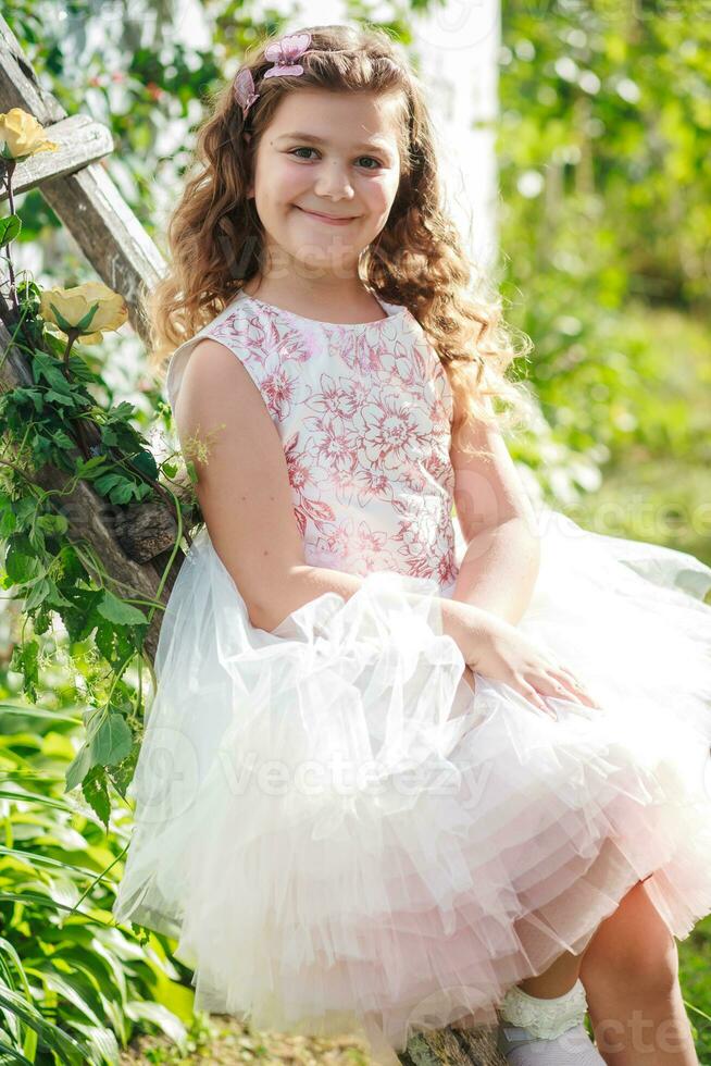 un hermosa niña se sienta en un de madera escalera decorado con flores en contra el fondo de naturaleza foto