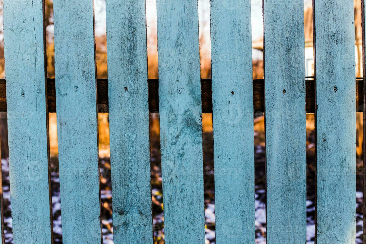 Brown fence made of wood. Wooden background with weathered wood. Painted blue paint fence rarely nailed planks. photo