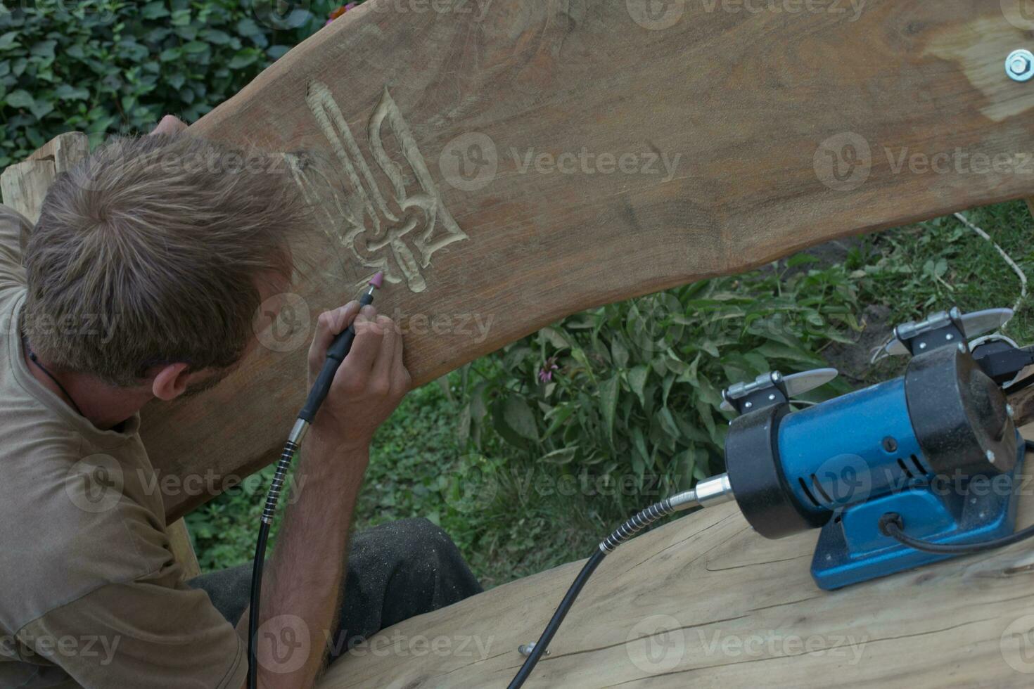 man with device cuts out coat of arms of Ukraine. photo