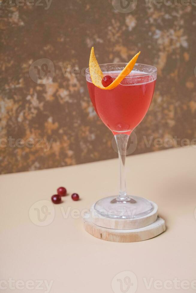 Pink alcoholic cocktail in steamed glass on wooden podium or pedestal photo