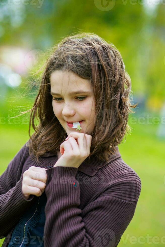 Beautiful girl among cherry flowers in spring. Portrait of a girl with brown hair and green eyes. photo
