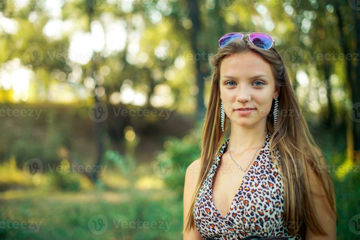 Beautiful girl in a light sarafan with developing hair on forest background. Girl is smiling standing. photo