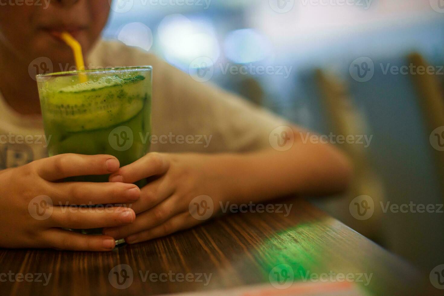 boy drinks from straws juice. Child holding a glass of cocktail. photo