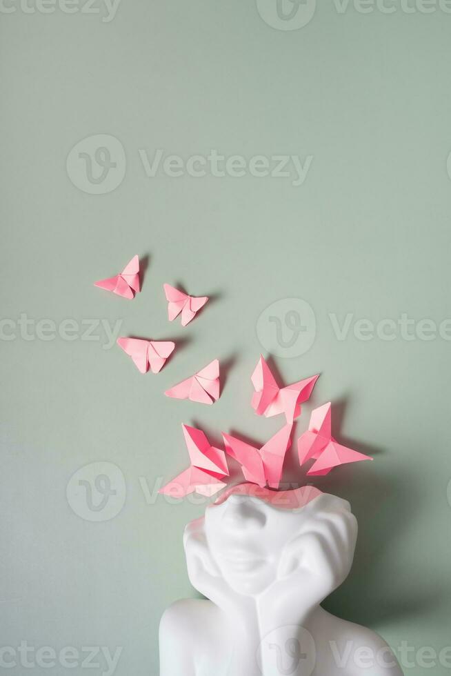 Mental health, mind care concept. A figurine of a head with butterflies on a colored background photo