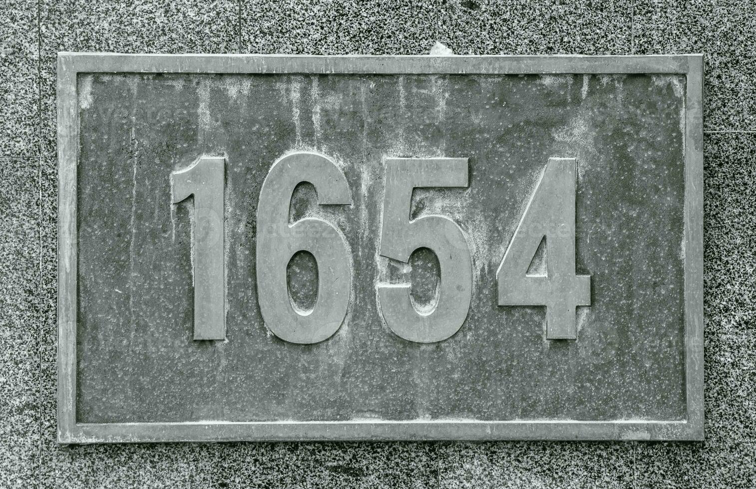 Cast bronze house number on stone wall concept photo. Street exterior metal board plate on wall. photo