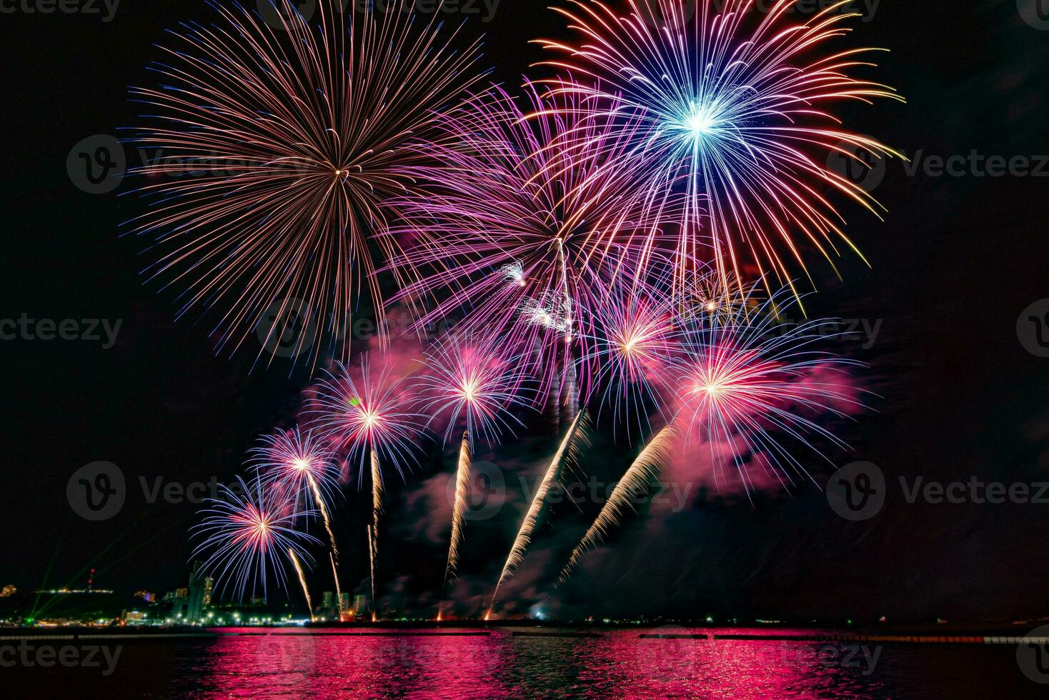 Amazing beautiful colorful fireworks display on celebration night, showing on the sea beach with multi color of reflection on water photo