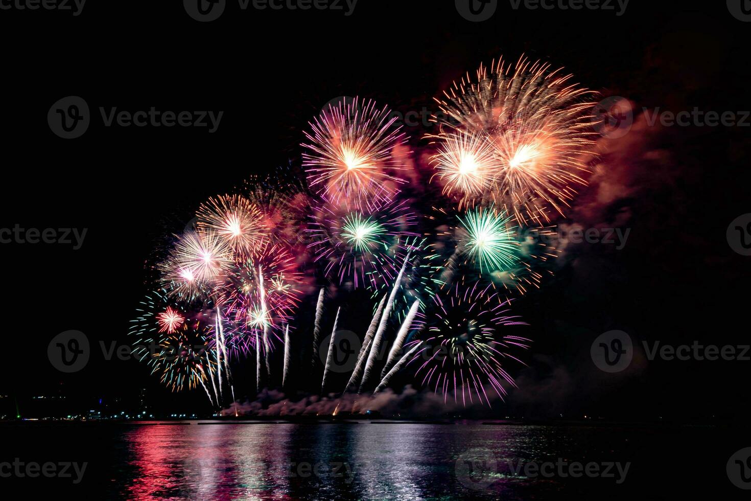 Amazing beautiful colorful fireworks display on celebration night, showing on the sea beach with multi color of reflection on water photo