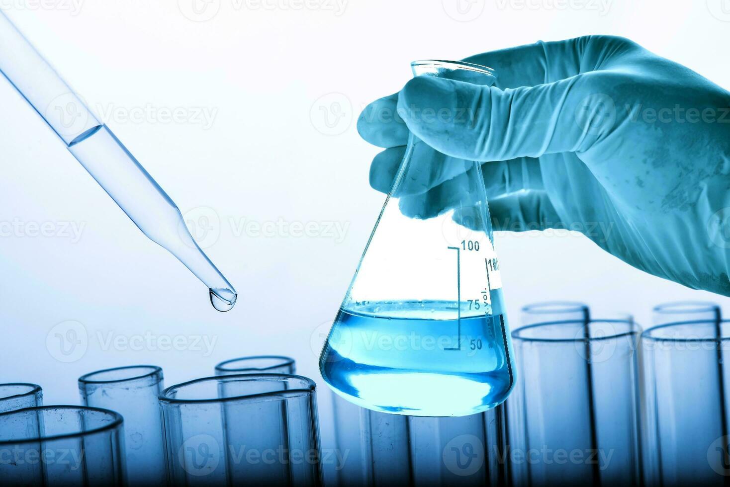 Flask in scientist hand with lab glassware background photo