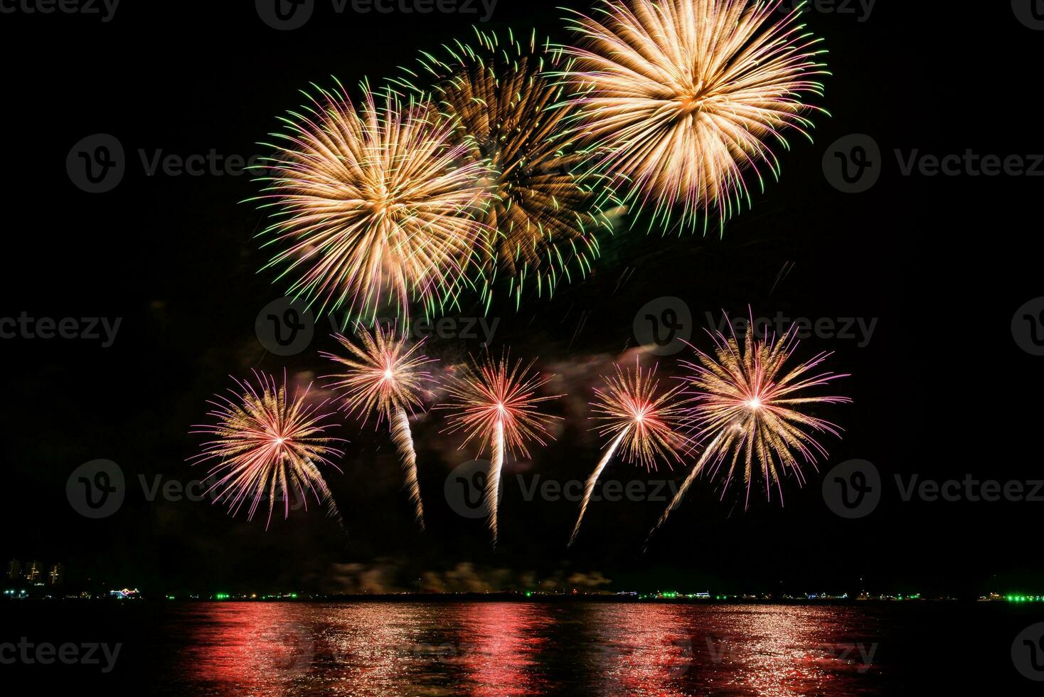 Increíble y hermoso colorido espectáculo de fuegos artificiales en la noche de celebración, que se muestra en la playa del mar con reflejos multicolores sobre el agua foto