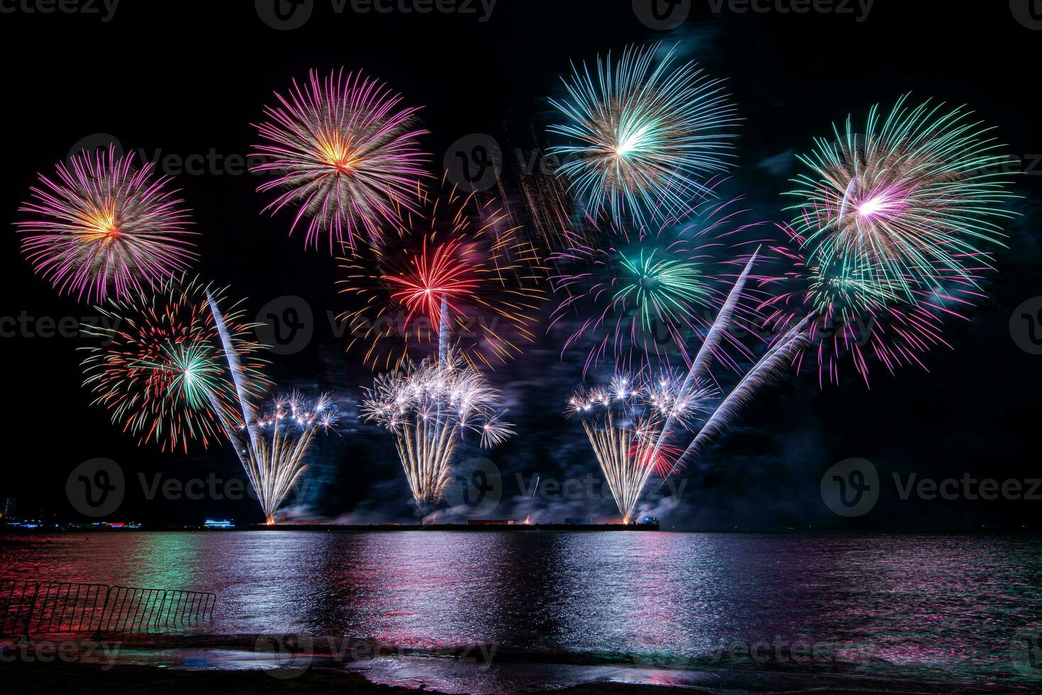 Amazing beautiful colorful fireworks display on celebration night, showing on the sea beach with multi color of reflection on water photo