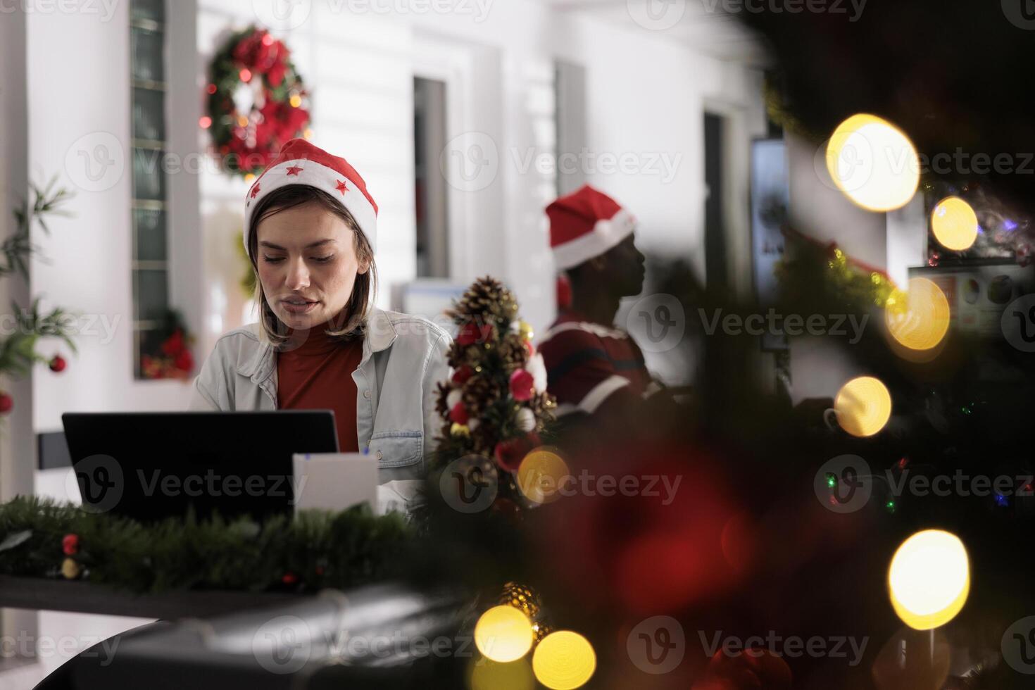 Businesswoman in festive decorated workspace working hard on computer tasks for upcoming project. Employee researches company startup plans during Christmas holiday season photo
