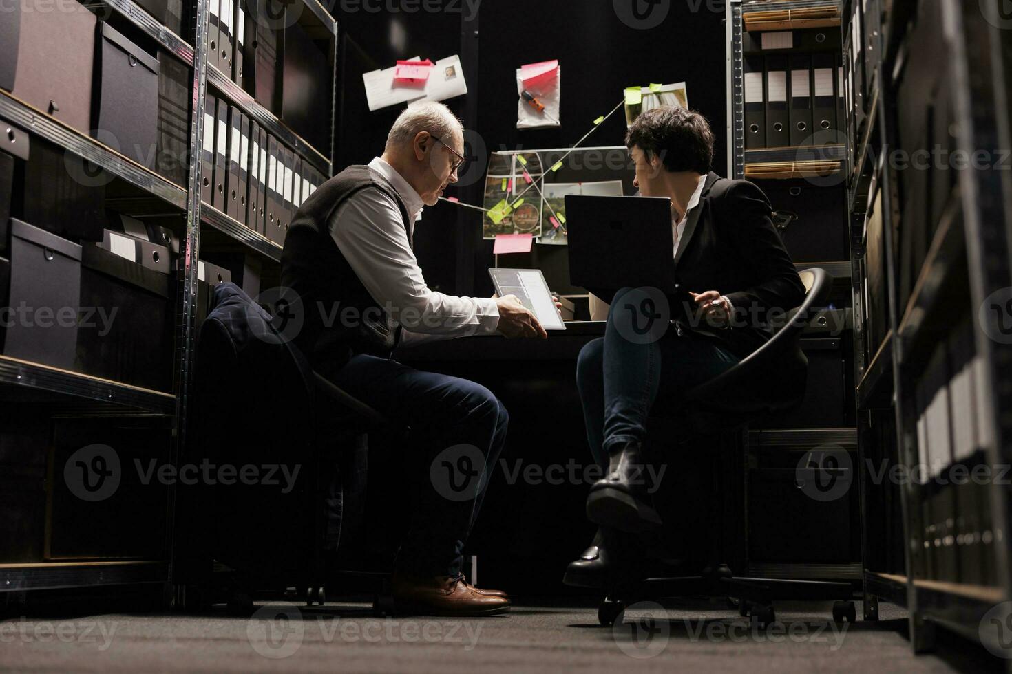 Elderly police officer examining crime evidence files, discussing criminology report with fbi agent. Investigators analyzing victim report discovery confidential information. Investigation concept photo