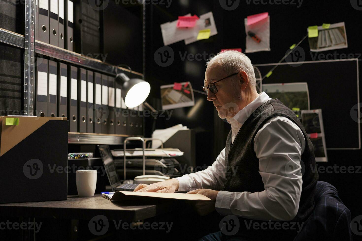 Elderly police officer analyzing confidential federal files, working at criminal investigations in arhive room. Senior private detective checking missing person case, looking at victim report photo
