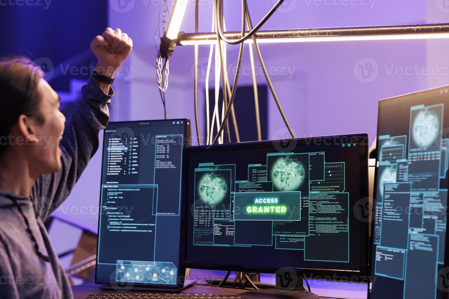 Hacker celebrating access granted to computer system and doing illegal activities. Young asian man raising fist in victory gesture after hacking database successfully in abandoned warehouse photo