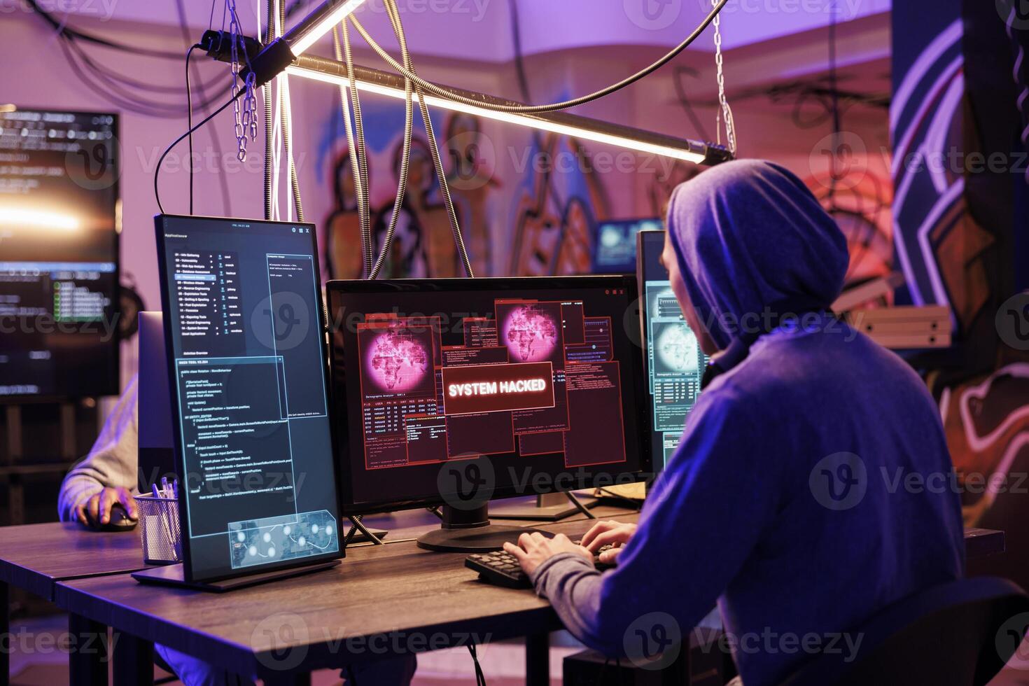 Criminal in hood successfully hacking into computer system in abandoned warehouse. Hacker gaining unauthorized access and stealing valuable data from database online server photo