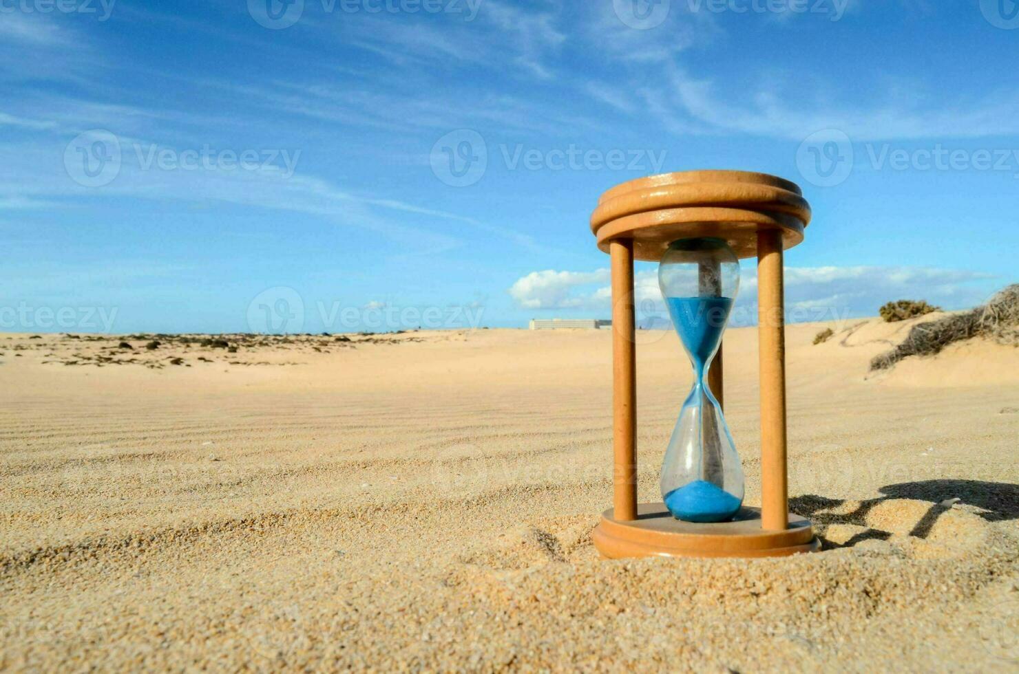un reloj de arena en el arena en un soleado día foto