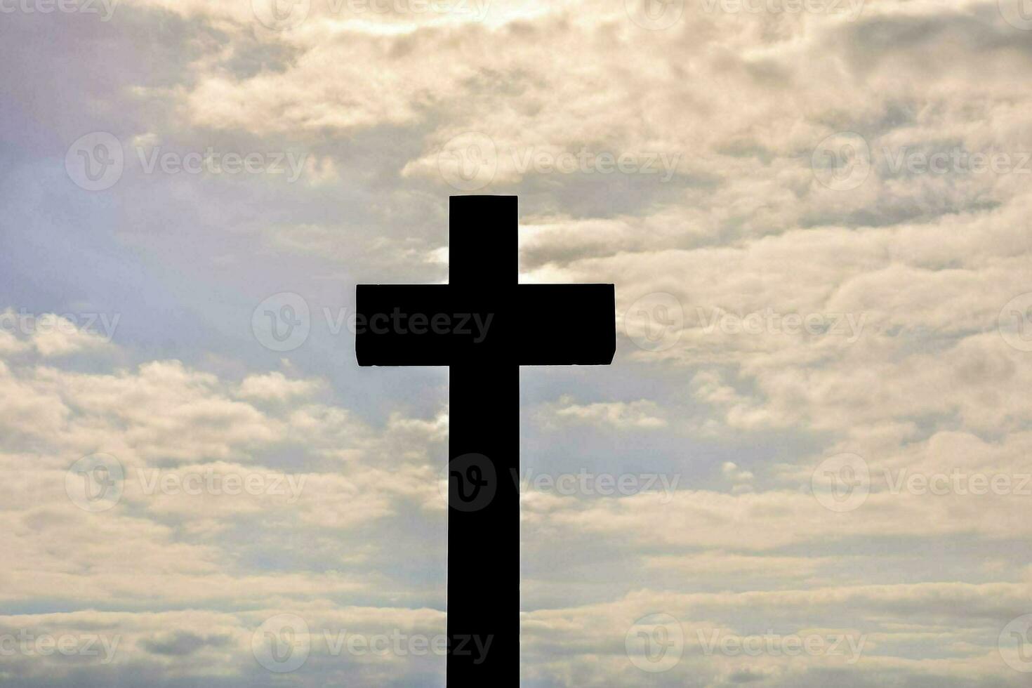 a cross is silhouetted against a cloudy sky photo