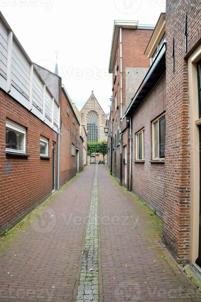 a narrow street with brick buildings and a church photo